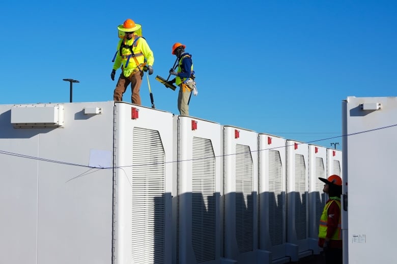 Workers check battery storage compartments